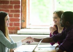 Three people talking and two of them handshaking