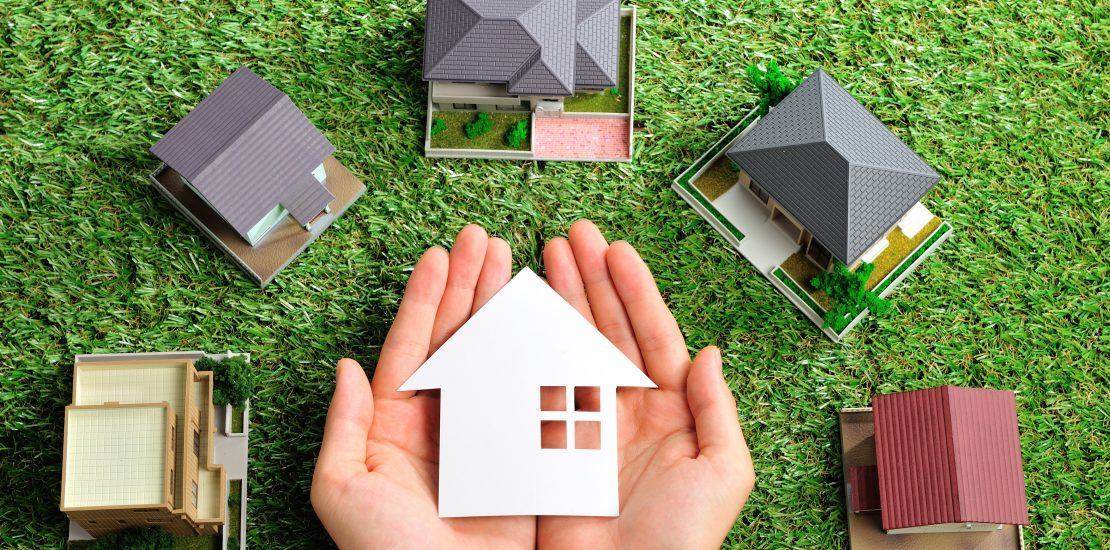 Five houses on the grass and one house being held