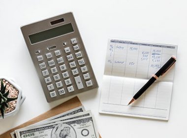 A calculator, pen, paper and money